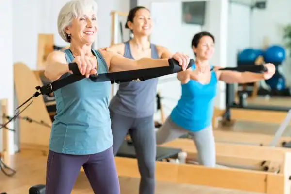 Toning Arms After 60: Empowering Womens Fitness Through Effective Weight Training 2 older woman doing weight training Watford and resistance in the gym to tone upper arms