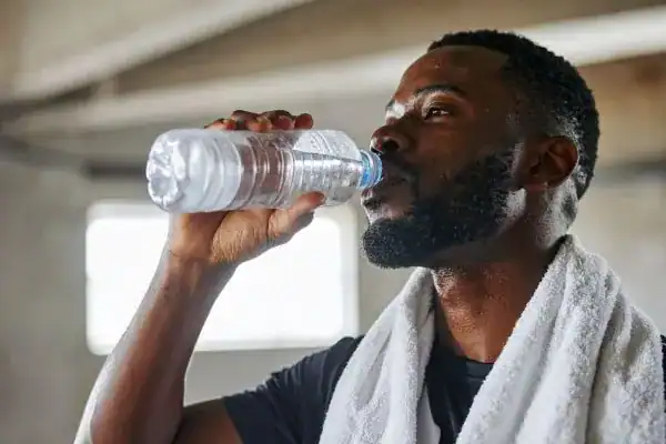 Image of man drinking water to improve hydration Watford after work out.